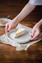 Delicious sweet dessert classical cheesecake New York on wooden rustic background. Woman hands serving slice of tasty cake on