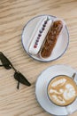 delicious sweet french eclairs and coffee in a coffee shop. Morning breakfast on a light table of a young girl. Royalty Free Stock Photo