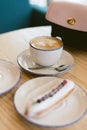 delicious sweet french eclairs and coffee in a coffee shop. Morning breakfast on a light table of a young girl. Coffee, handbag an Royalty Free Stock Photo