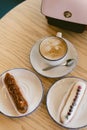 delicious sweet french eclairs and coffee in a coffee shop. Morning breakfast on a light table of a young girl. Coffee, handbag an Royalty Free Stock Photo