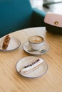 delicious sweet french eclairs and coffee in a coffee shop. Morning breakfast on a light table of a young girl. Coffee, handbag an Royalty Free Stock Photo