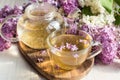 Delicious sweet herbal tea with lilac scent, glass cup and teapot with hot drink Royalty Free Stock Photo