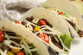 Delicious tacos with fried meat, vegetables and cheese on white table, closeup Royalty Free Stock Photo