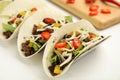 Delicious tacos with fried meat, vegetables and cheese on white wooden table, closeup Royalty Free Stock Photo