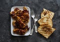 Delicious tapas - baked chicken breast wrapped in bacon, grilled bread on a dark background, top view