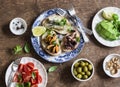 Delicious tapas - sandwiches sardines, mussels, octopus, grape, olives, tomato and avocado on wooden table, top view. Royalty Free Stock Photo