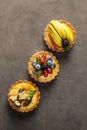 Delicious tarts with fruits and berries on grey background