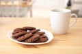 Delicious and tasty chocolate cookies in a plate and a white cup of coffee in a bright kitchen Royalty Free Stock Photo
