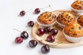 delicious and tasty cupcakes with chocolate chips and fresh ripe cherries on a wooden tray on a white table Royalty Free Stock Photo