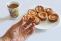 Delicious tasty homemade muffin bite and hold with the fingers of the hand. Coffee and served muffins on a plate to have a Royalty Free Stock Photo