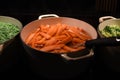 Close up food photography image of hot cooked vegetables of carrots peas and cabbage simmering in pots ready to eat