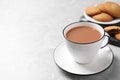 Delicious tea with milk in white cup near cookies on grey table. Space for text