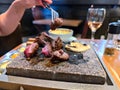 Delicious tender pink beef steak tips are grilled on a stone grill on a restaurant table