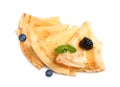 Delicious thin pancakes with berries on white background, top view