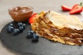 Delicious thin pancakes with chocolate spread and blueberries on grey table, closeup
