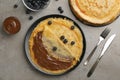 Delicious thin pancakes with chocolate spread and blueberry on grey table, flat lay