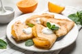 Delicious thin pancakes with oranges and cream on table