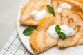 Delicious thin pancakes with oranges and cream on table, closeup