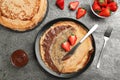 Delicious thin pancakes served with chocolate paste and strawberries on grey table, flat lay Royalty Free Stock Photo