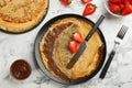 Delicious thin pancakes served with chocolate paste and strawberries on white marble table, flat lay Royalty Free Stock Photo