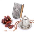 Delicious tropical dates on a silver plate and Turkish coffee with Islamic holy book Quran and rosary beads on isolated white back Royalty Free Stock Photo