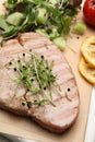Delicious tuna steak with microgreens on parchment paper, closeup