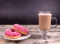 A delicious two pink donuts with white sprinkles and a cup of coffee with milk Royalty Free Stock Photo