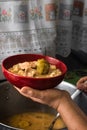 Delicious typical Central American dish called pozole being served by an adult lady in a red bowl and a pot almost full of this Royalty Free Stock Photo