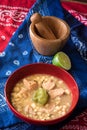 Delicious typical Central American dish called pozole served in a red bowl full of stew made of meat, corn, chili and other Royalty Free Stock Photo