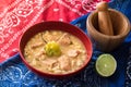 Delicious typical Central American dish called pozole served in a red bowl full of stew made of meat, corn, chili and other Royalty Free Stock Photo