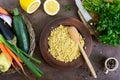 Delicious useful porridge cous cous in a clay plate and raw fresh vegetables in a basket, greens, lemon.