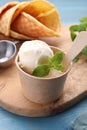 Delicious vanilla ice cream with mint in paper cup on light blue wooden table Royalty Free Stock Photo