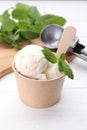 Delicious vanilla ice cream and mint in paper cup on white wooden table Royalty Free Stock Photo