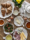 Delicious varied breakfast, brunch - croissants, eggs, ham, cheese, butter, apricot jam, fresh vegetable salad on a wooden table, Royalty Free Stock Photo