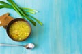 Delicious vegetable soup in a brown bowl with onions and herbs on a blue wooden table next to black bread and a metal spoon Royalty Free Stock Photo