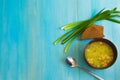 Delicious vegetable soup in a brown bowl with onions and herbs on a blue wooden table next to black bread and a metal spoon Royalty Free Stock Photo