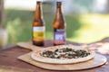 Delicious veggie pizza served on a wooden cutting board with two bottle of beers Royalty Free Stock Photo