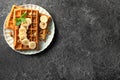 Delicious waffles with banana slices and nuts on grunge background