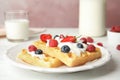 Delicious waffles with fresh berries served on wooden table against pink background Royalty Free Stock Photo