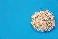 Delicious white airy fried popcorn in a plate on blue background