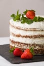 Delicious white cream icing cake with strawberry on the black board. Naked cake with cream, decorated with strawberries and mint. Royalty Free Stock Photo