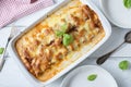 Cannelloni casserole with bolognese and bechamel sauce with mozzarella cheese topping white wooden background.