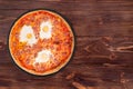Delicious whole pizza with beef sausages, eggs and bacon or Brunch pizza on a slate plate on the wooden table Royalty Free Stock Photo