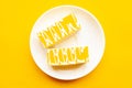 Delicious yellow cakes on a plate, top view. Bright yellow background