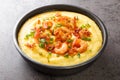 Delicious yellow grits with cheese, shrimps and bacon close-up in a plate. horizontal