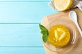 Delicious yellow jelly lemon slices and mint on light blue wooden table, flat lay. Space for text