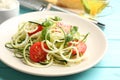 Delicious zucchini pasta with cherry tomatoes, basil and grated cheese served on light blue wooden table, closeup Royalty Free Stock Photo