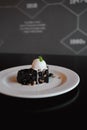 Deliciously prepared brownie dessert is displayed on a white plate with a scoop of icecream