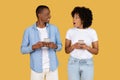 Delighted African American man and surprised woman engaged with their smartphones Royalty Free Stock Photo