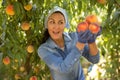 Delighted Asian female gardener holding ripe peaches in garden